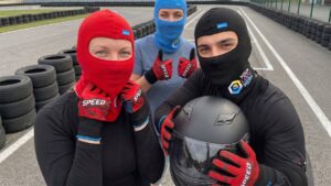 Młody kierowca gokarta w kasku i personalizowanych rękawicach nylonowych z logo - gadżety na tor kartingowy.