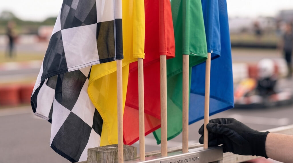 Flagi kartingowe na torze kart-rental — szachownica, żółta, czerwona, zielona i niebieska